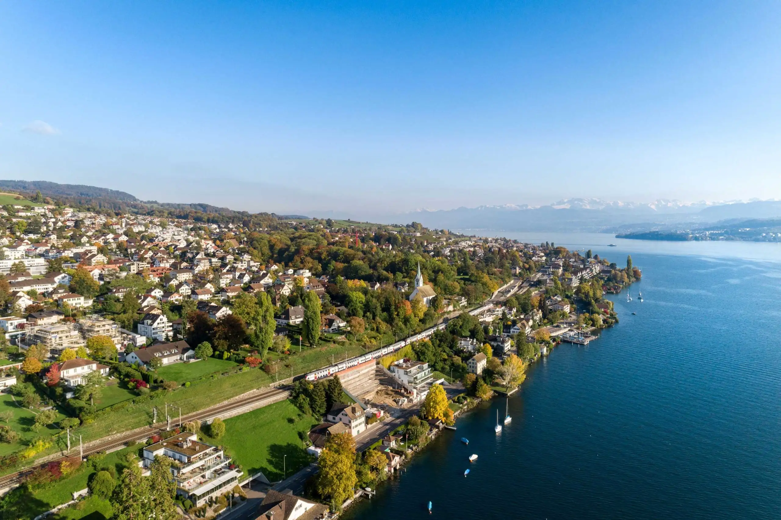 Aerial view over Herrliberg and Lake Zurich, with the Swiss Alps visible in the distance